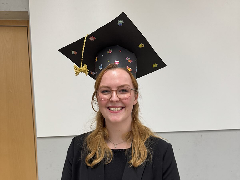 Portrait of Emma Peters wearing a doctoral hat.