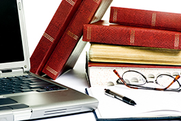 Das Bild ziegt typische Gegenstände fürs Studium: Computer, Bücher und Stift.