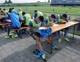 Junge Fussballspieler füllen einen Fragebogen aus.