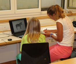 Eine Studienleiterin erklärt einem Mädchen eine Computeraufgabe.
