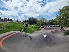 Zwei Biker fahren über Hindernisse im Bikepark.