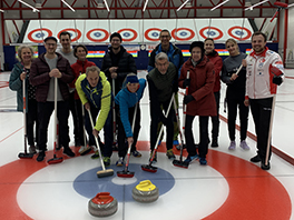 Eine Gruppe mit Curling-Ausrüstung auf einem Eisfeld.